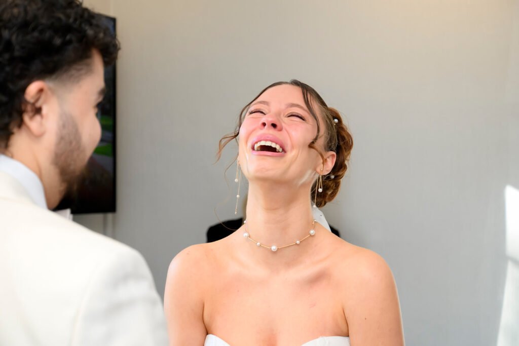 Close up of bride laughing and crying at the same time during wedding vows.